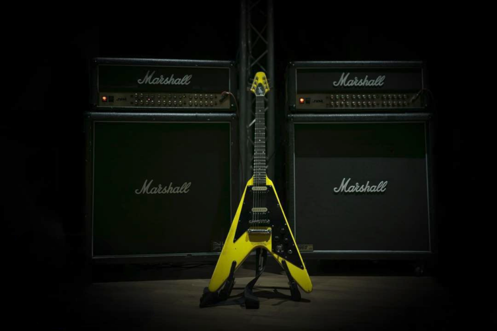 Photo of a yellow flying V guitar in front of Marshall Amps at Powerhouse Studios Surrey