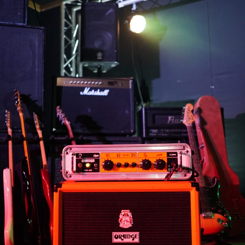 An Orange Amp at Powerhouse Studios, surrounded by guitars and with a Marshall amp behind it