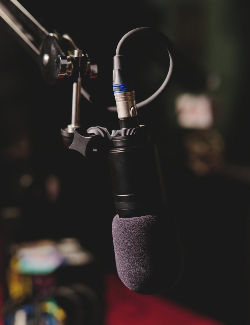 Contemporary professional condenser microphone placed on blurred background of studio in dim light and ready for recording podcast