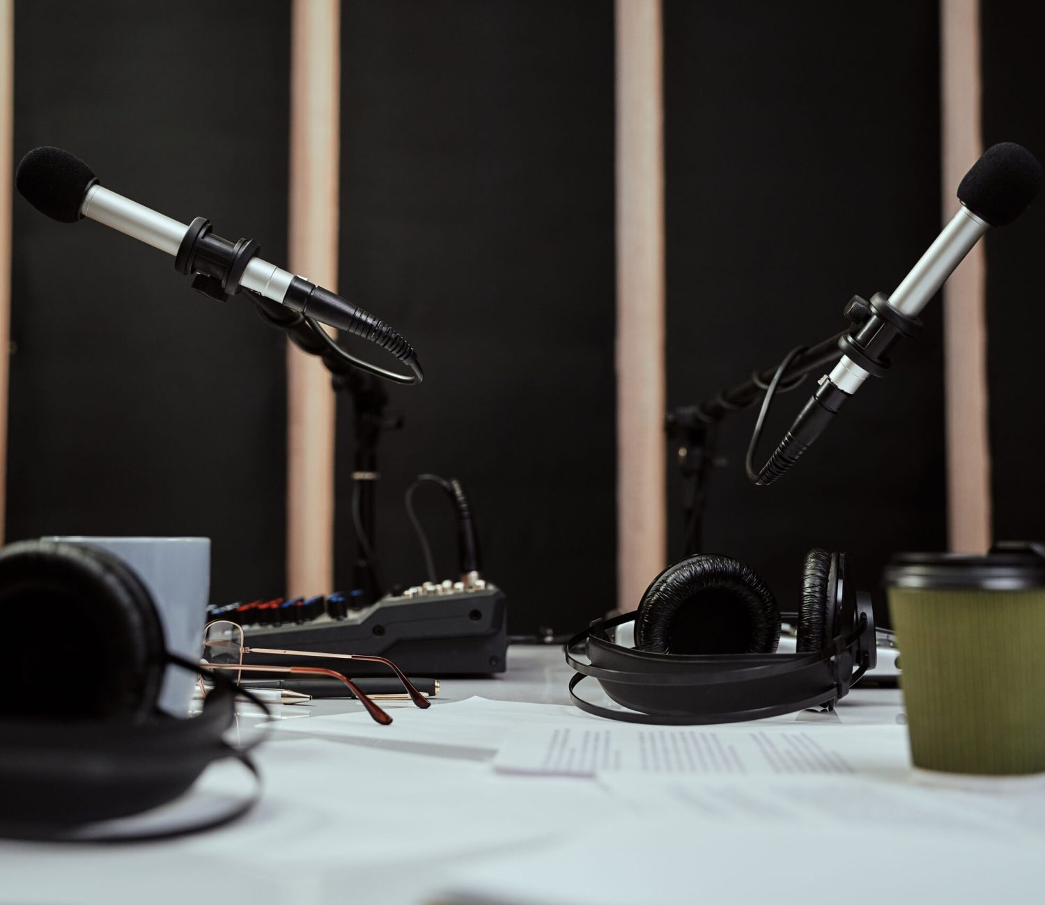 Podcast recording at Powerhouse Studios, with two mics on a table, mixing desk, headphones and a coffee with written notes on a table in a recording room